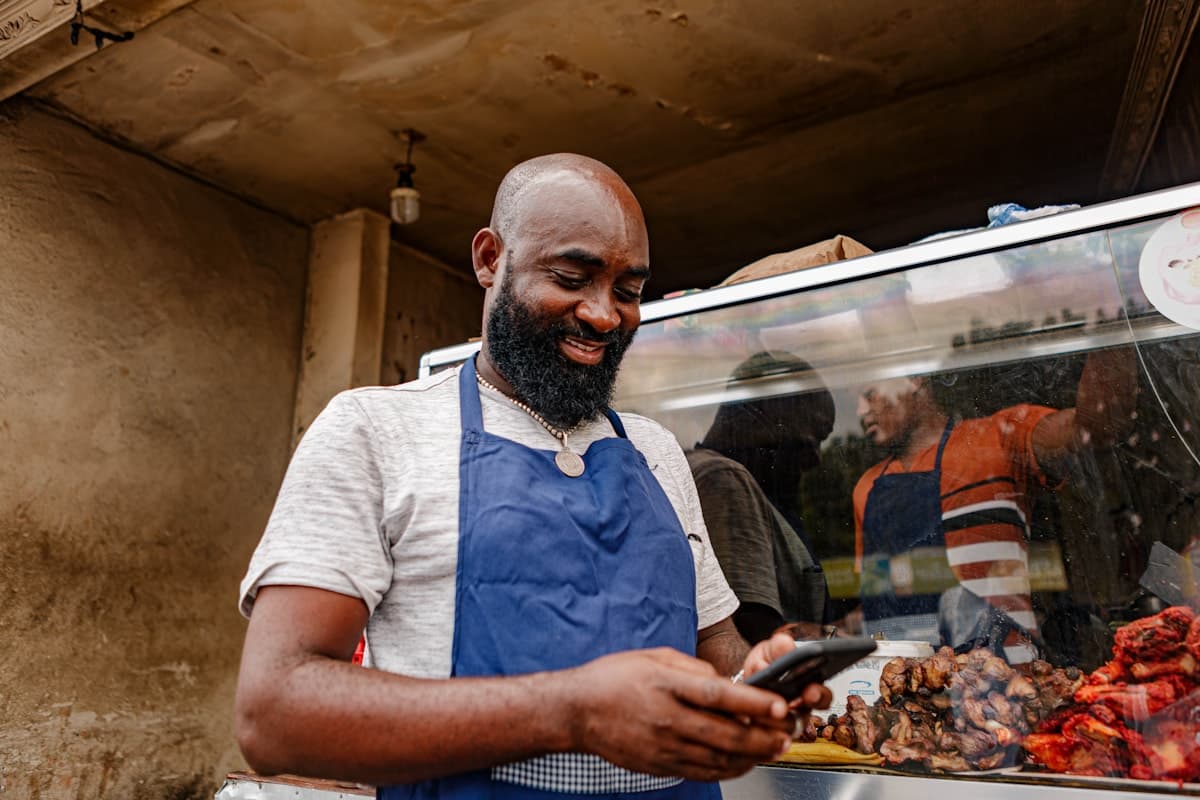 A shop owner behind his counter, checking his phone between customers